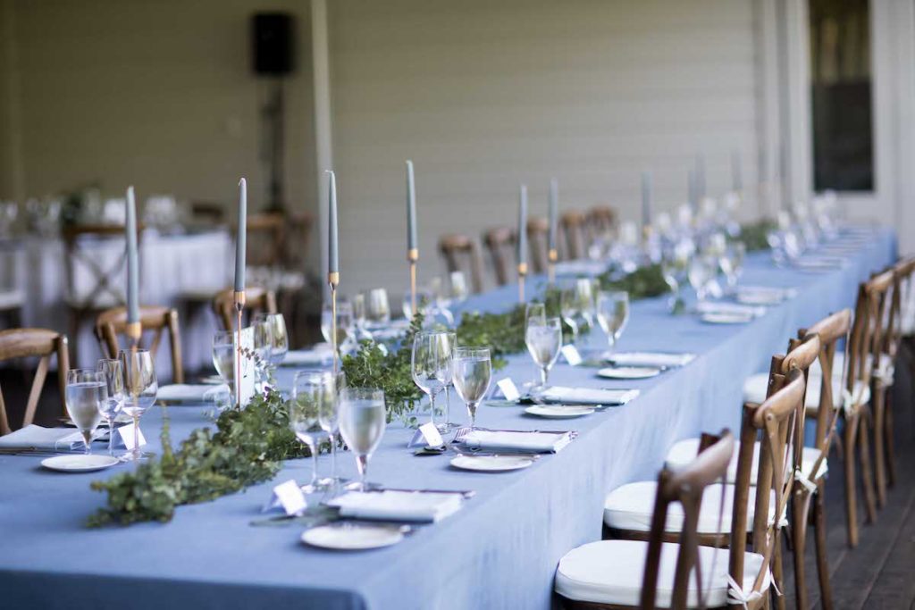 Dusty blue head table with gold candles and green garland