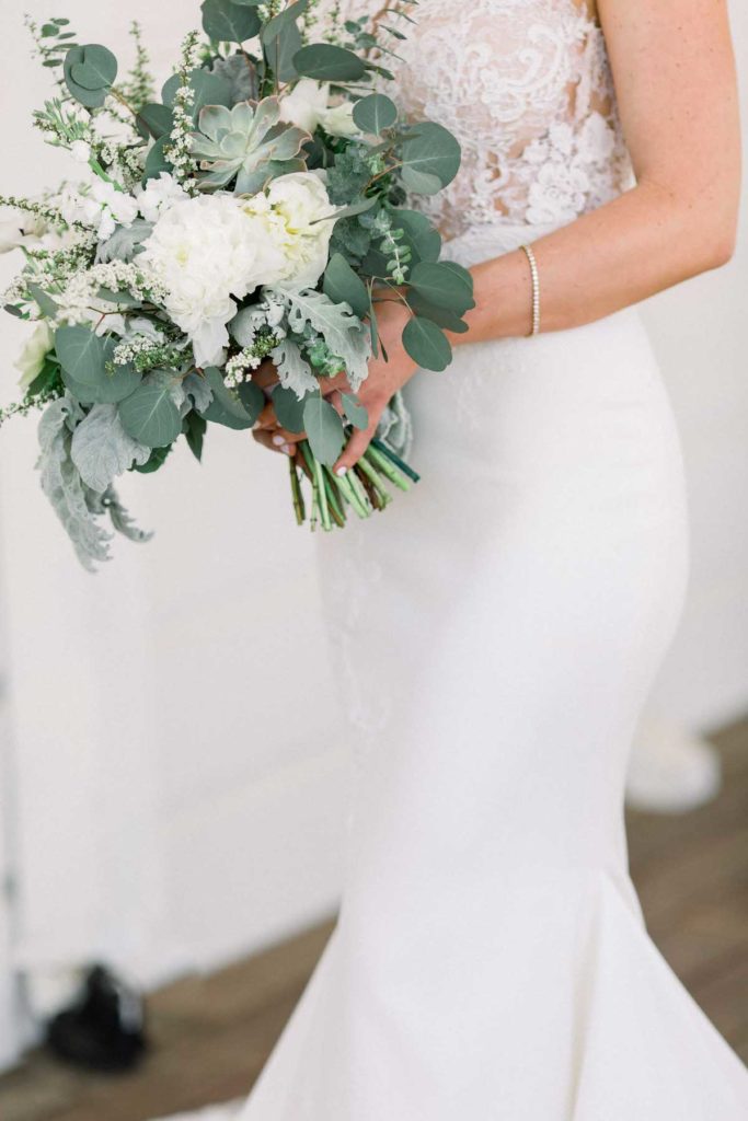 Side view of bride holding bouquet with green and white flowers