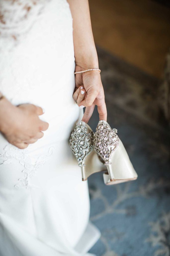 Bride holding white wedding shoes