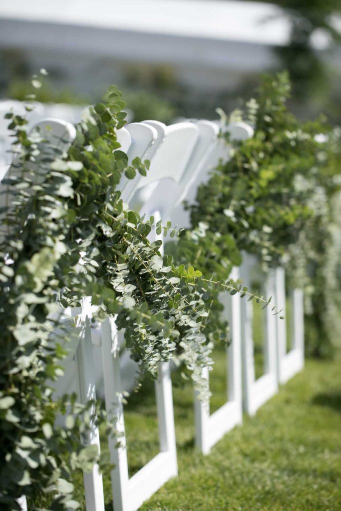 white ceremony chairs with green garland