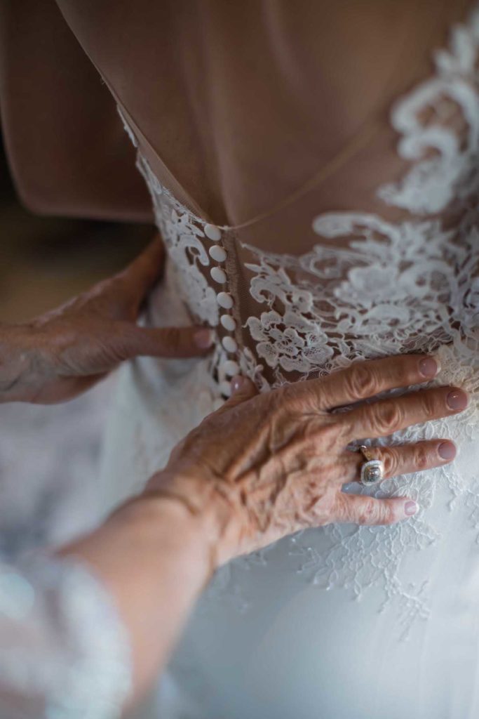 Mother of the bride helping bride into wedding dress