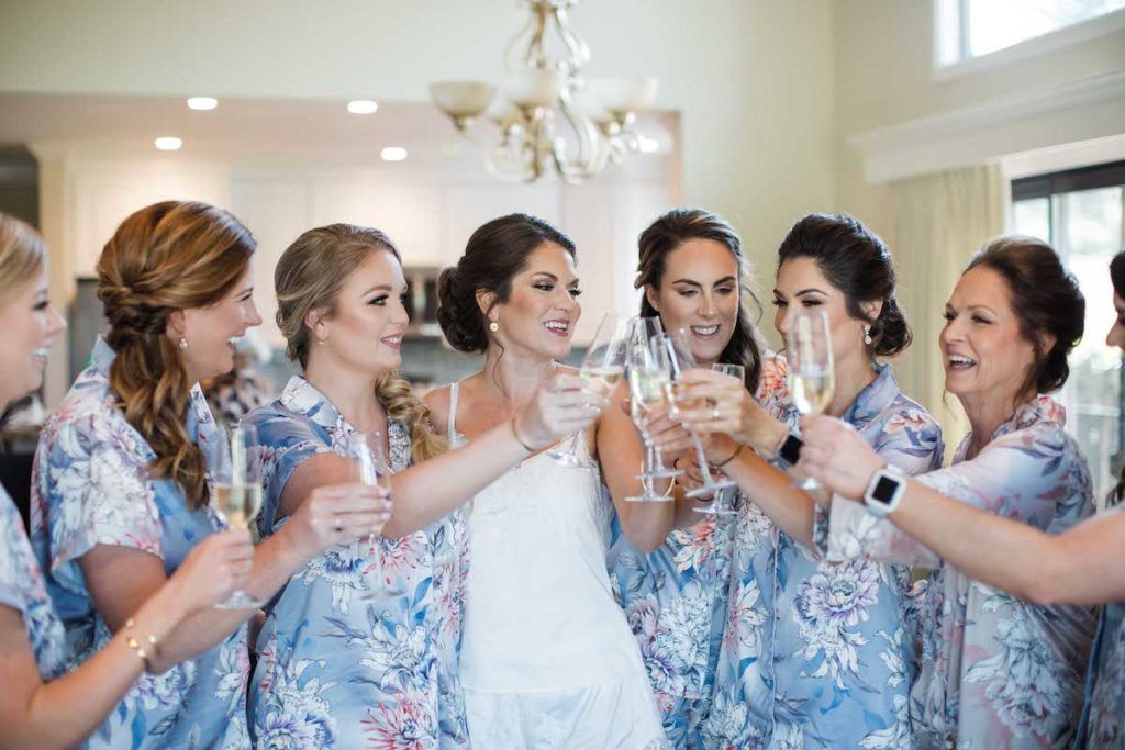 Bridesmaids & bride making toast with champagne glasses in silk pajamas
