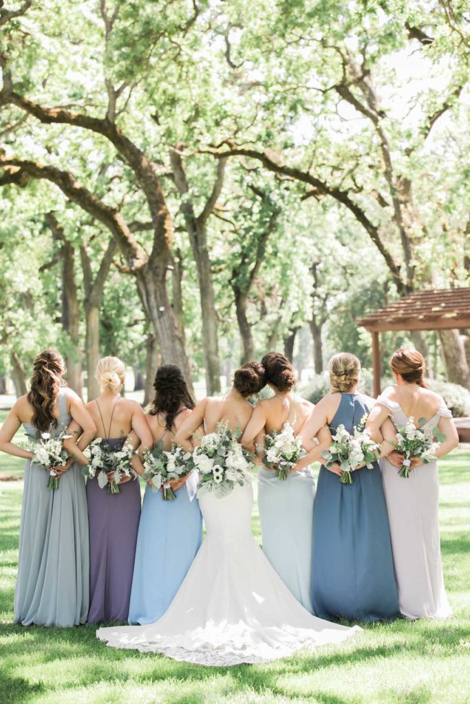 Bride and bridesmaids with backs facing camera, holding bouquets