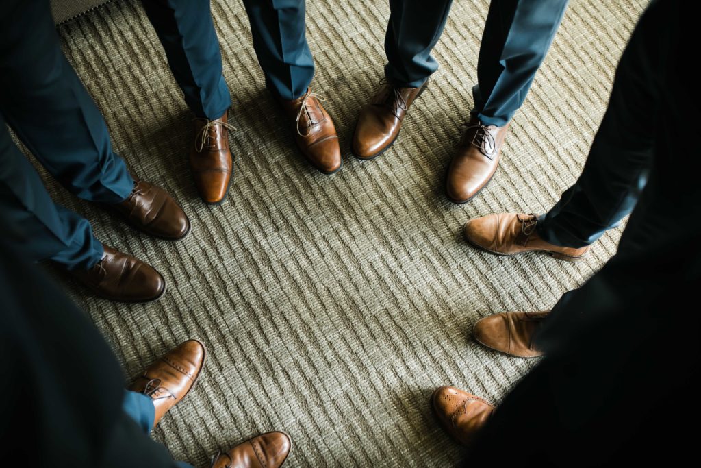 Groomsmen standing in circle in blue suits and brown shoes