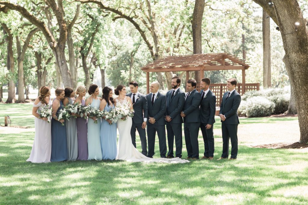 Bridesmaids in varying shades of blue and groomsmen in gray blue suits
