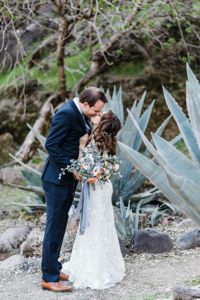 bride and groom kiss in front of large succulents at Calistoga Ranch